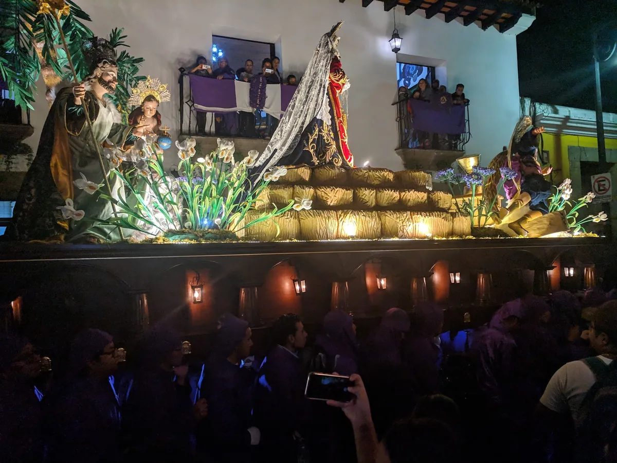 Procesion de Semana Santa con cucuruchos morados cargando un anda en Antigua Guatemala