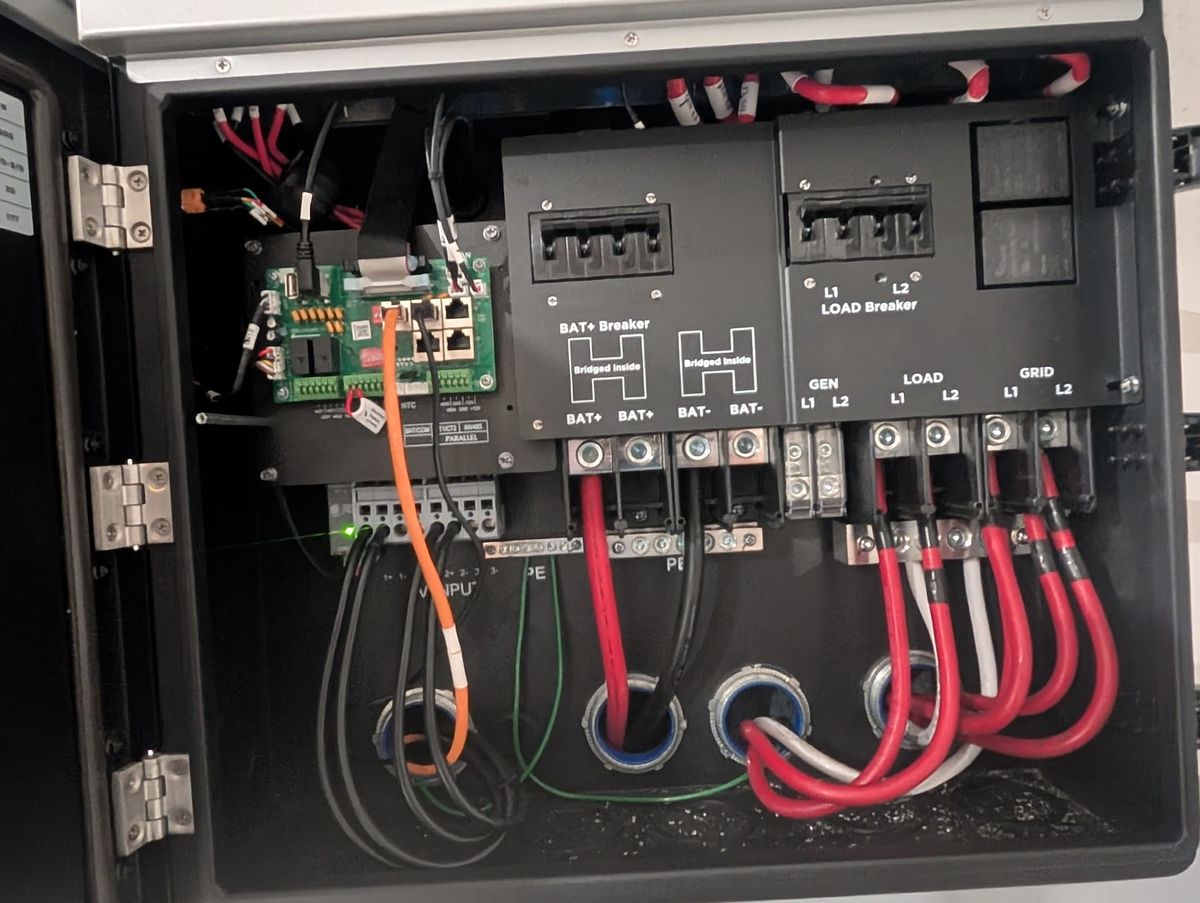 Vista interior del cableado del inversor hibrido Luxpowertek mostrando conexiones BAT+, LOAD y GRID