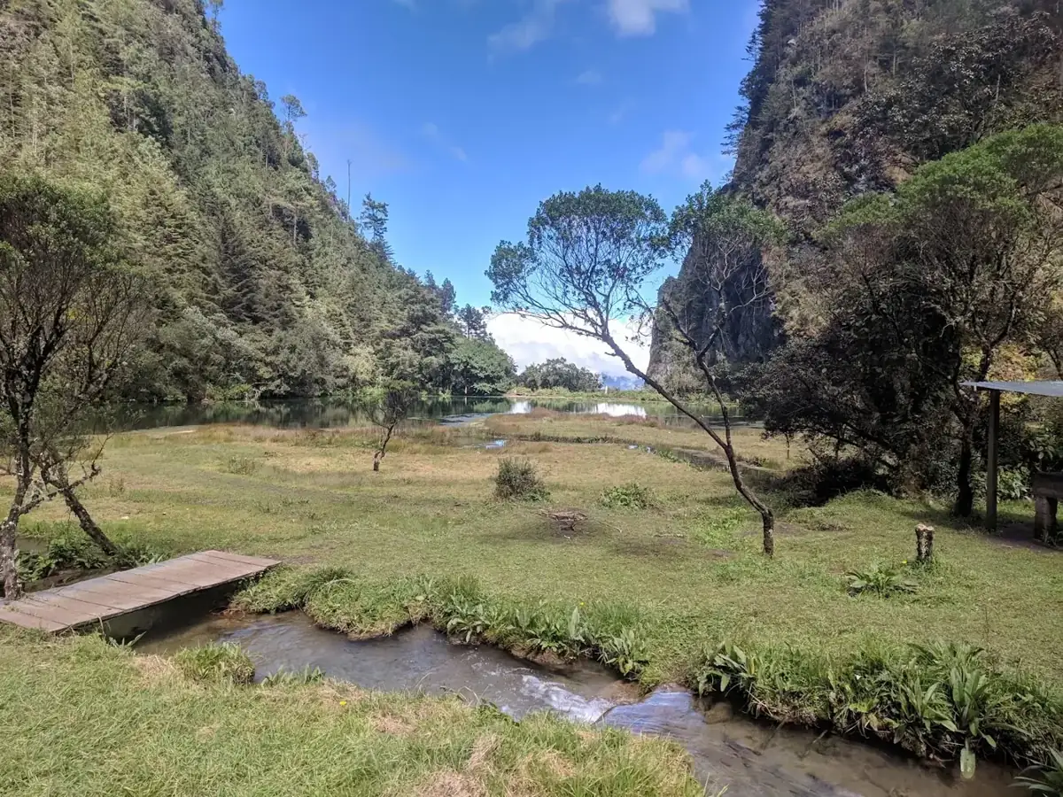 Laguna Magdalena meadow and stream between forested cliffs, Huehuetenango