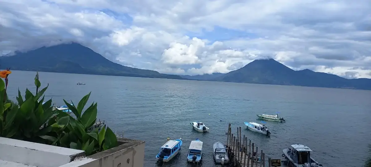 Lake Atitlan with boats at a dock and volcanoes across the water